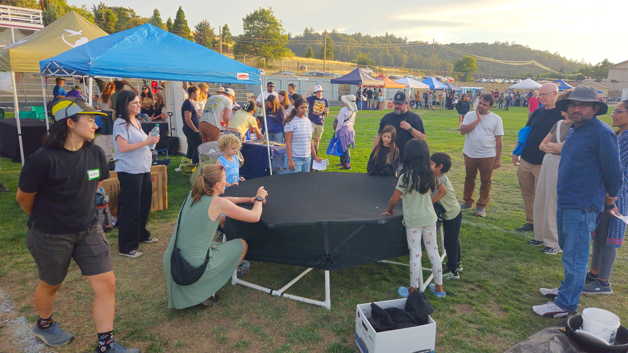 Families and kids gathered around the stretched-fabric spacetime demo at the San Diego Dark Sky Festival in Julian
